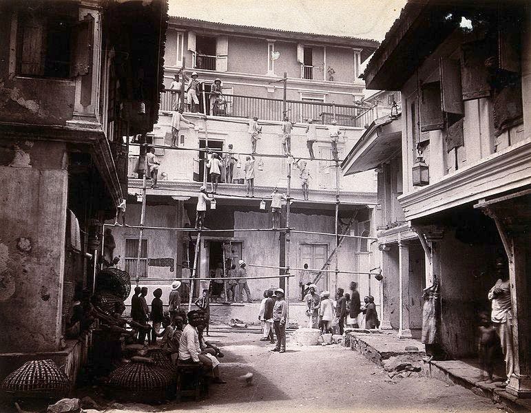 A plague house being whitewashed by men standing on scaffolding in Bombay